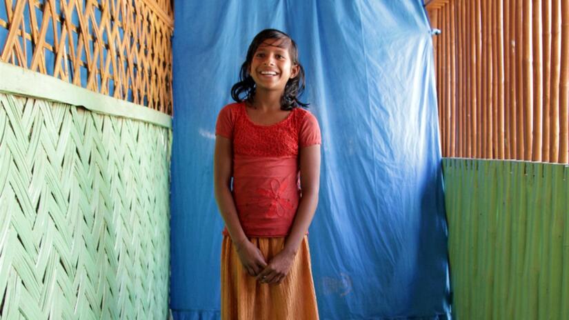 Minara, a girl from Myanmar stands in a community safe space in Burmapara camp, Cox's Bazar where she plays, reads and embroiders with her friends.