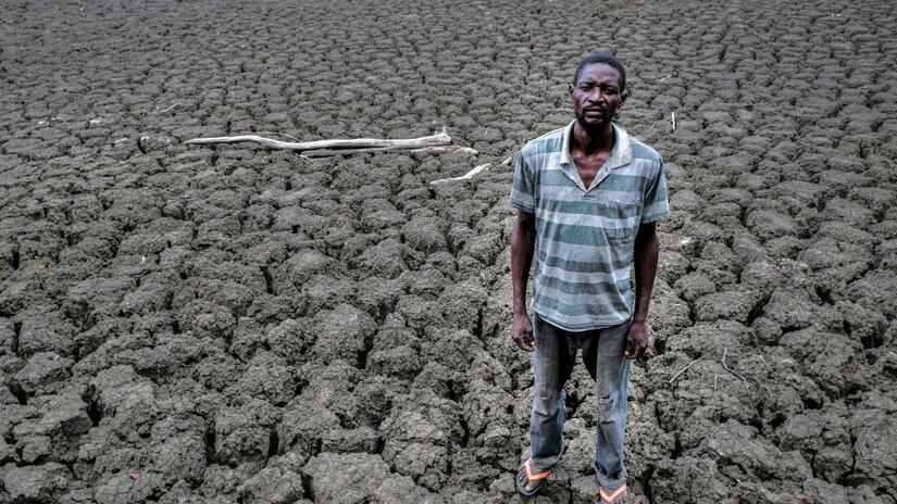In Zambia, Brian stands in an empty dam to show the scale of the emptiness. The dam ran dry, with no sign of filling, as rains were already delayed by two months.