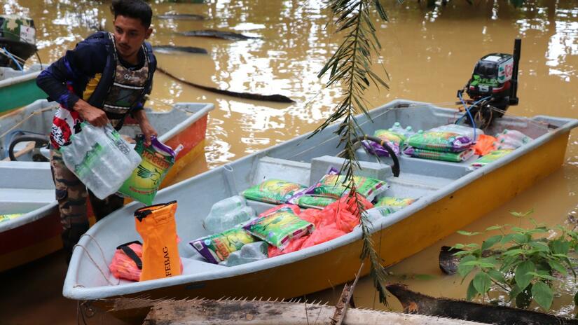 A Malaysian Red Crescent volunteer unloads relief supplies from a boat to assist communities in Terengganu state affected by severe flooding in summer 2021