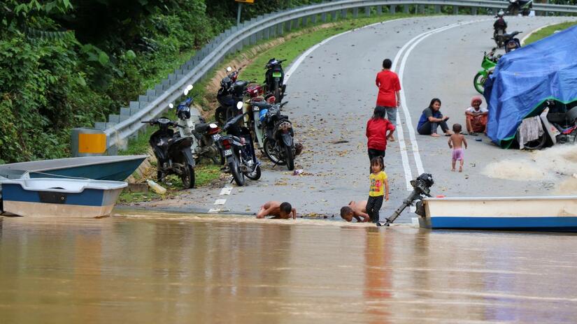 Malaysian Red Crescent volunteers provide assistance to families camping on roadsides waiting for flood waters to recede to reach their homes in summer 2021