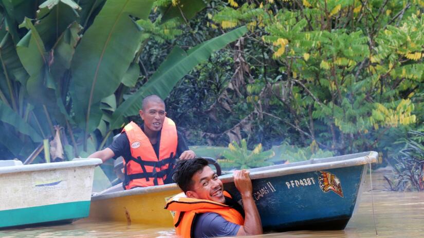 Malaysian Red Crescent volunteers steer a small boat through flood water in summer 2021 to reach stranded communities with essential supplies.