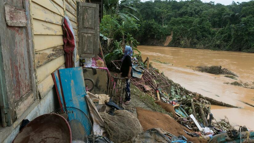 A woman looks through the window of her house in Terengganu, Malaysia that was badly damaged by severe flooding in summer 2021