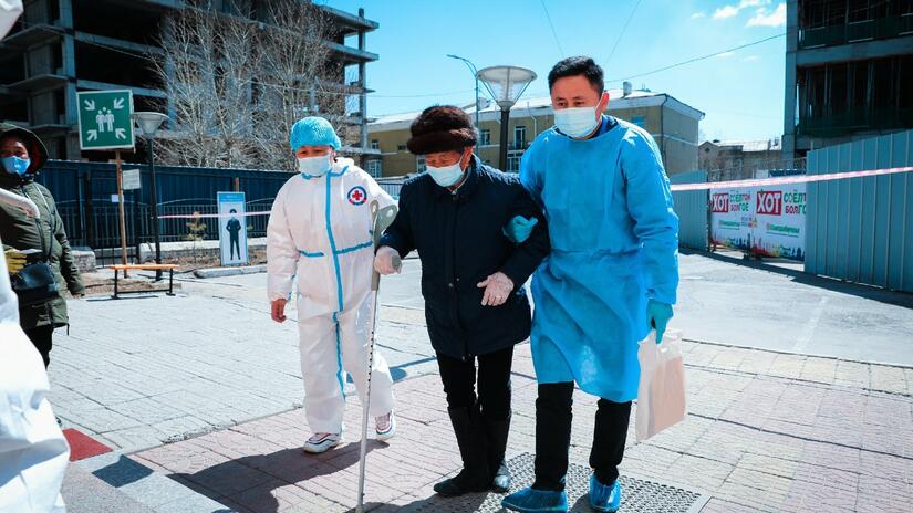Two Mongolia Red Cross volunteers help escort an elderly man to a vaccination centre to receive his COVID-19 vaccine in May 2021. Trained Red Cross volunteers have been supporting Mongolia’s vaccination campaign across all 21 provinces and nine districts.