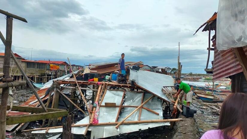 A man stands on his devastated home after Typhoon Rai slammed into the east coast of the Philippines. 