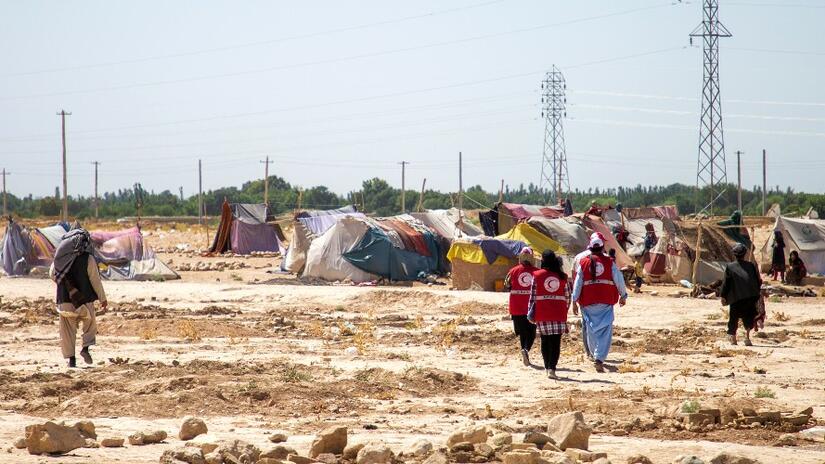 Afghan Red Crescent volunteers walk towards a small camp of internally displaced people in Balkh Province, Afghanistan in summer 2021. The Afghan Red Crescent has been delivering a cash transfer program to help people cope with multiple shocks including drought, COVID-19 and conflict.