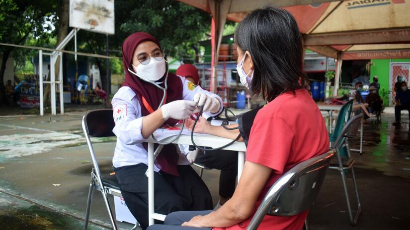 A volunteer from the Indonesian Red Cross in Tangerang, Indonesia performs a health check up on a woman before administering a dose of COVID-19 vaccine in January 2022.