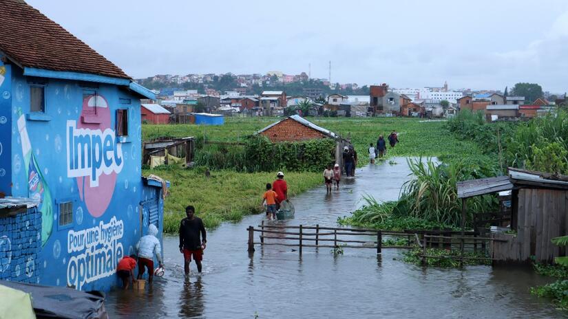 People in Madagascar walk through floods caused by heavy rains in January 2022. The Malagasy Red Cross is working with the government to provide relief assistance, health services and shelter to those affected.