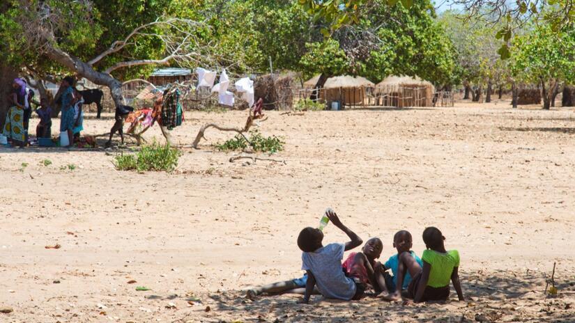 النساء والأطفال في مقاطعة إنهامبان في موزمبيق يجلسون تحت الأشجار في الظل ويشربون الماء خلال فترة الحر الشديد والجفاف