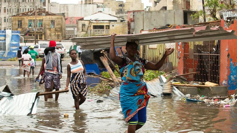 People walk through a flooded section of Praia Nova in Beira, Mozambique after Cyclone Idai hit in March 2019. Idai caused widespread destruction to homes, infrastructure and livelihoods.