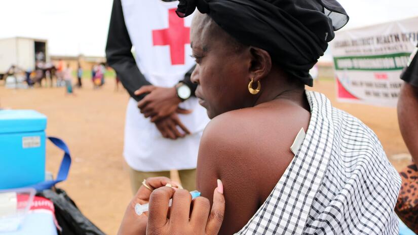 A woman in rural Zambia receives her first COVID-19 vaccine with the support of a Zambia Red Cross mobile health team.