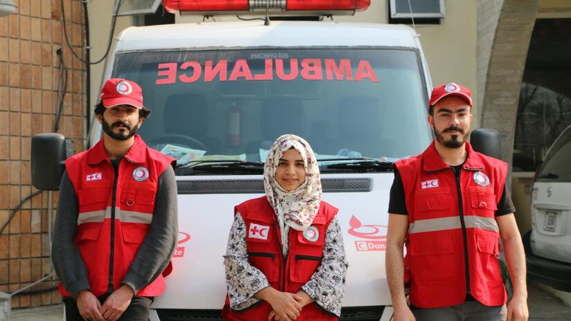 Pakistan Red Crescent Society volunteers stand next to an ambulance outside the National Society's headquarters in Islamabad