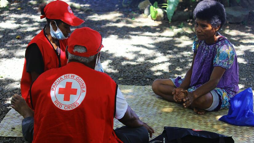 Papua New Guinea Red Cross volunteers sit down with a woman and respond to her concerns about getting the COVID-19 vaccine as part of its community engagement work to encourage people to get vaccinated.