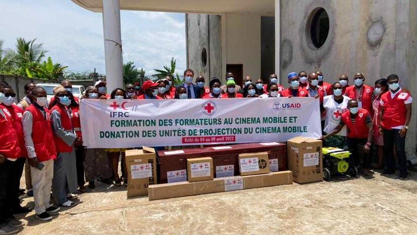 Representantes de la delegación del Clúster de África Central de la IFRC entregan oficialmente cinco equipos de cine móvil a la Cruz Roja de Camerún en abril de 2022, en presencia de numerosos voluntarios y voluntarias.