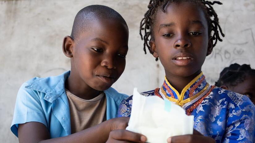 A young boy and girl in Mozambique inspect a sanitary pad as part of an education session on menstrual hygiene management following Cyclone Idai hitting the country in 2019. The class, delivered by the Mozambique Red Cross and IFRC, aimed to improve the children's knowledge of menstrual hygiene and tackle harmful period stigma and misinformation that can hold girls back.