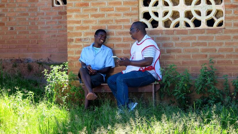 A Malawi Red Cross volunteer speaks to a teenage boy to understand his perceptions and knowledge around periods, as part of a joint research project with the Swiss Red Cross