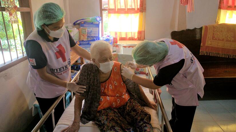 Thai Red Cross Society volunteers vaccinate an elderly woman against COVID-19 in her hospital bed in Nakhon Si Thammarat province in May 2022.