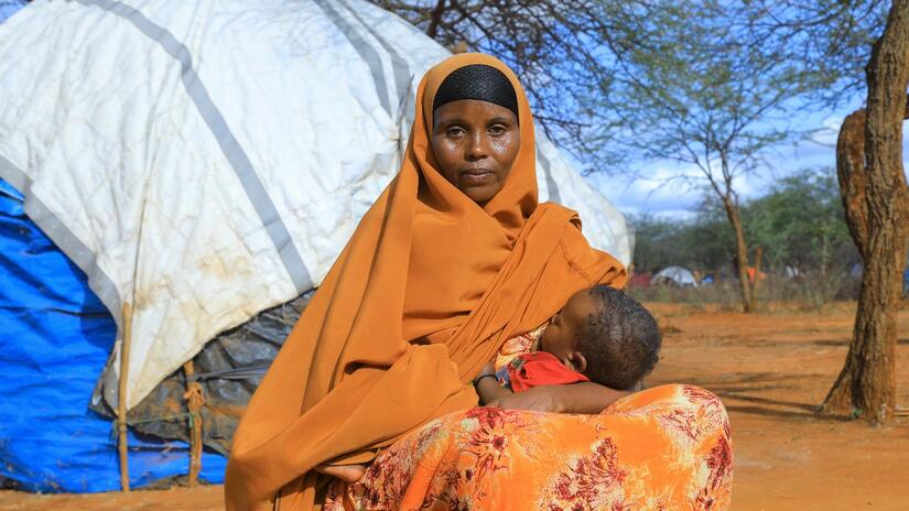 Adoy, a woman from Moyale, breastfeeds her son outside their home in June 2022. Due to prolonged drought in the region, she is struggling to feed her family. The Ethiopian Red Cross is providing cash grants to her community to help people cope with the impacts of drought on their lives and livelihoods.