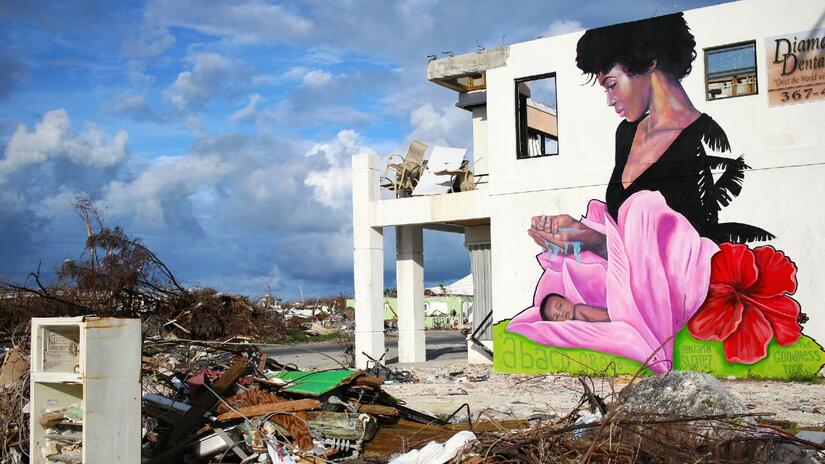 لوحة جدارية نابضة بالحياة لامرأة تحمي طفلها على جانب أحد المباني القليلة المتبقية في أباكو، جزر الباهاما، بعد أن أحدث إعصار دوريان دمارًا كبيراً في أواخر عام 2019.