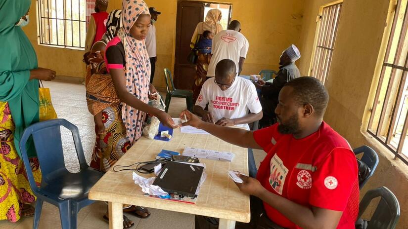 Unas madres reciben dinero en efectivo durante la distribución de cupones de efectivo de la IFRC en Lapai LGA, Estado de Níger. Esta ayuda en efectivo les permitirá comprar los alimentos que necesitan para alimentarse y alimentar a sus hijos.
