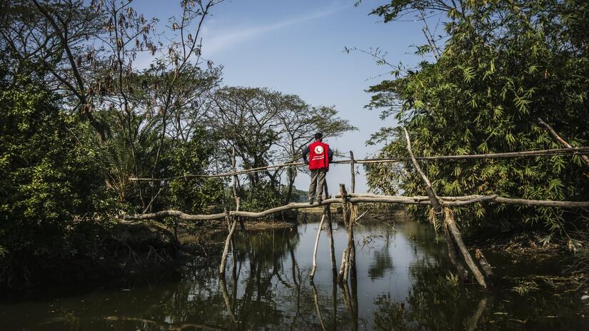 A Bangladesh Red Crescent volunteer stands on a bridge and looks out to sea. Every year, thousands of lives are saved by cyclone preparedness measures and early warning systems in which volunteers sound the alarm, evacuate communities and provide people with first aid and vital assistance.