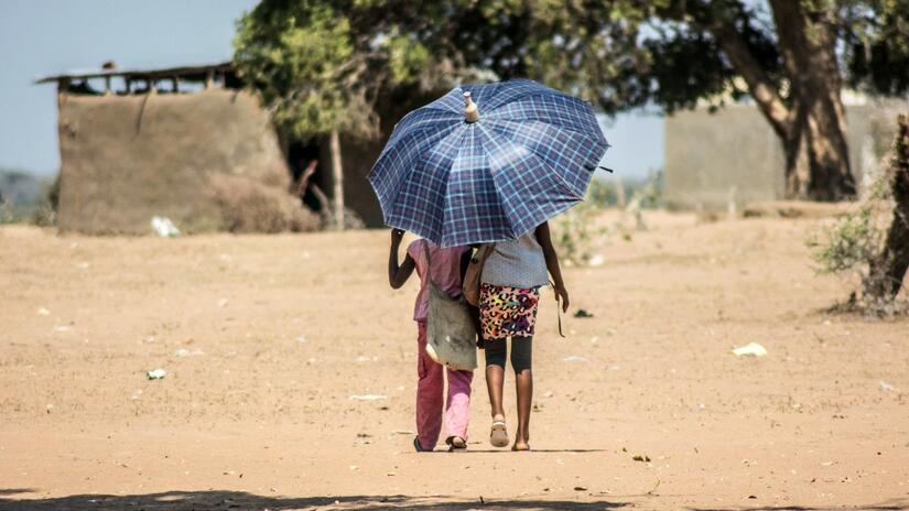 Two children walk beneath a sun umbrella to try and keep cool in Chichongole village in Mozambique.