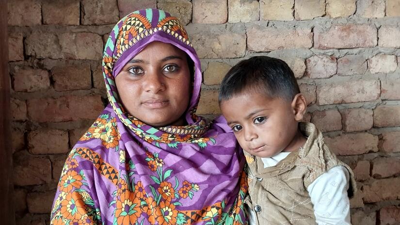 Jamila, madre de cuatro hijos de la provincia de Sindh, afectada por las inundaciones en Pakistán, sostiene en brazos a uno de sus hijos.