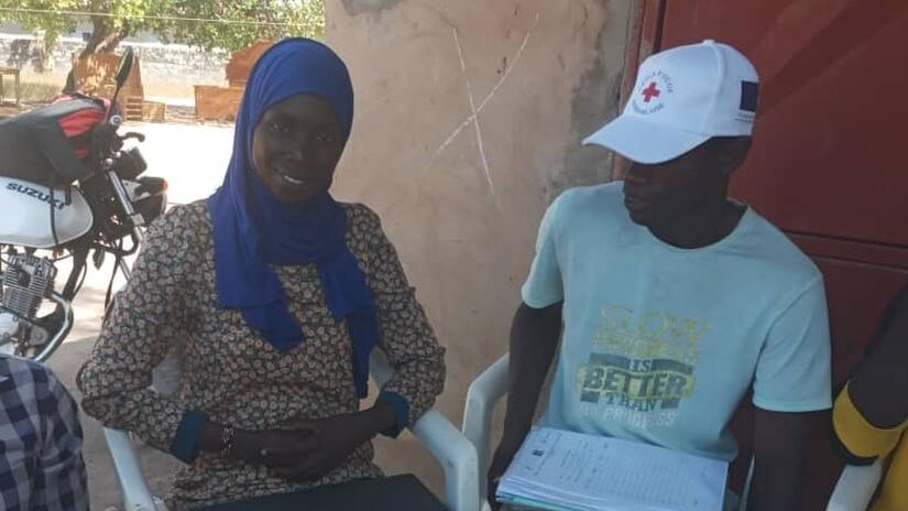 Mariama Mballo, trabajadora social senegalesa, sentada con un voluntario de la Cruz Roja Senegalesa en el Punto de Servicio Humanitario de Kolda.