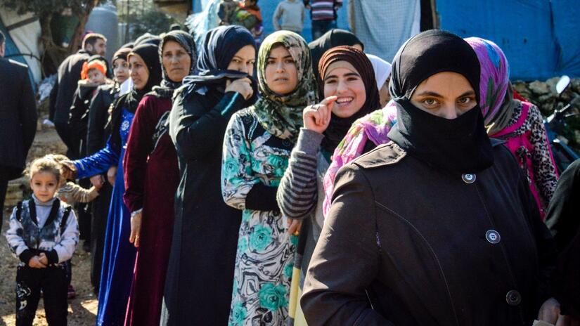 Refugees from Syria in Ketermaya refugee camp, Lebanon, stand in line to receive women’s emergency kits from the Lebanese Red Cross.