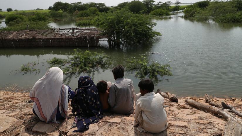 عائلة في منطقة سوجوال بإقليم سيند في باكستان تنظر إلى منزلها الذي غمرته فيضانات 2022 المدمرة. 