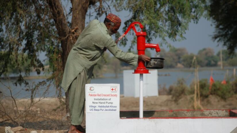 Un homme recueille de l'eau potable à partir d'une nouvelle pompe manuelle installée par le Croissant-Rouge du Pakistan dans le village de Habibulla Khoso, dans la province de Sindh, au Pakistan.