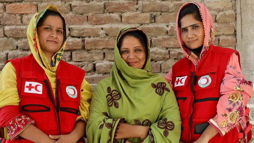 Three female Pakistan Red Crescent volunteers attend training on how to distribute critical relief items to those impacted by flooding in August 2022. Training includes learning about protection, gender and inclusion, community engagement and how to maintain the dignity of affected people throughout the distribution cycle.