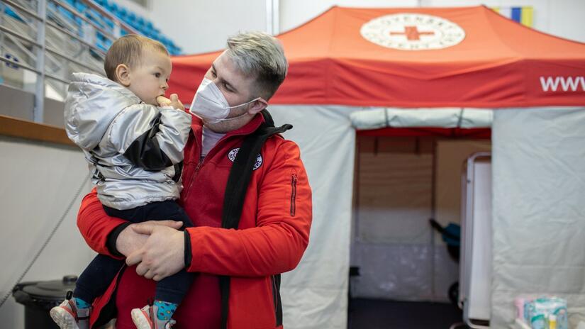 A Slovak Red Cross volunteer offers a little boy from Ukraine some snacks at a Humanitarian Service Point in Hummene, Slovakia, in March 2022.