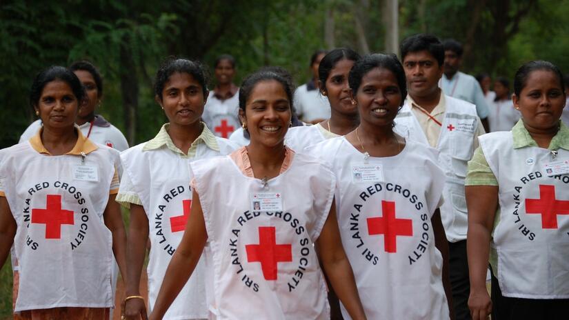 A group of female Sri Lanka Red Cross Society volunteers smile as they walk along together in their volunteering uniforms.