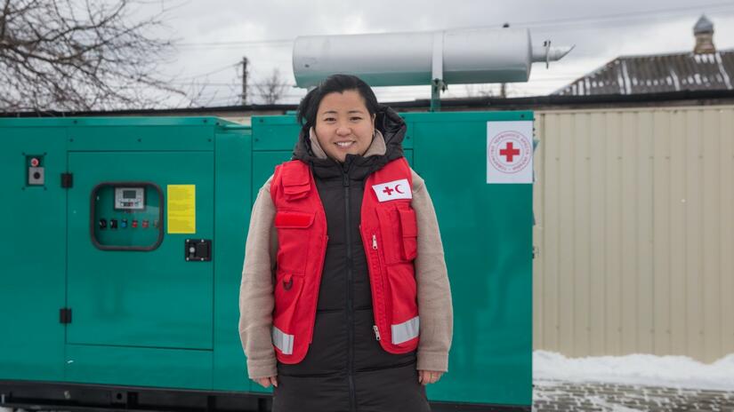 Jamie Wah, IFRC Health Coordinator in Ukraine, stands in front of a newly-donated generator at the relocated Bakhmut hospital in Ukraine.
