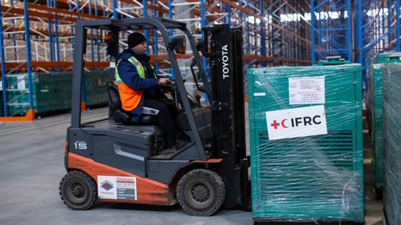 A warehouse worker uses a forklift to move a high-power generator in preparation for delivery to Ukraine where it will be used to provide power, heat and light to vulnerable communities.