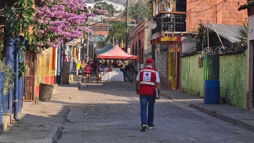 Stanley, volontaire de la Croix-Rouge hondurienne, marche dans une rue tranquille de sa ville natale de Copan Ruinas, au Honduras, vêtu de son gilet de la Croix-Rouge.