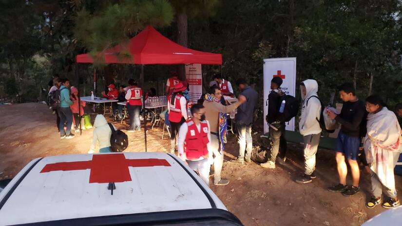 Un grupo de personas que migran por Honduras esperan en fila para recibir apoyo de los voluntarios de la Cruz Roja Hondureña en un Punto de Servicio Humanitario en el oeste del país a principios de 2023.
