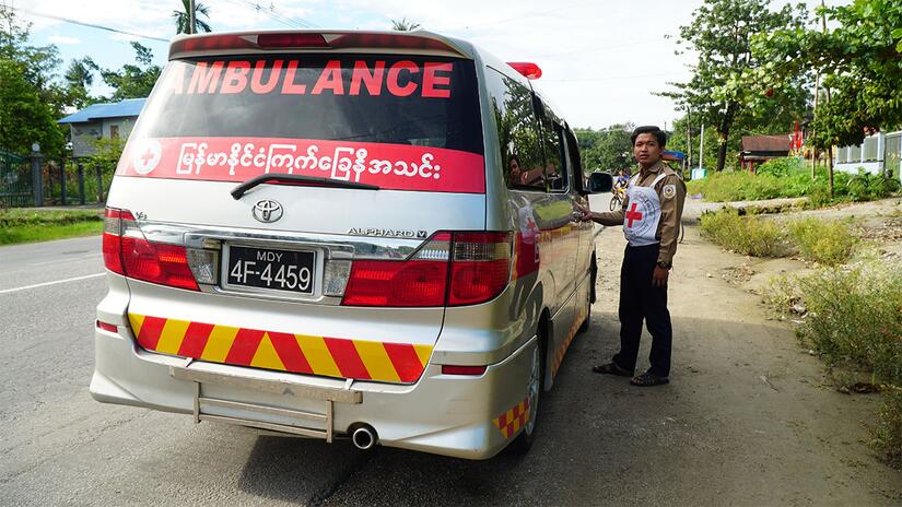 A Myanmar Red Cross ambulance worker stands next to one of their many ambulances used to provide urgent medical assistance to people across the country.