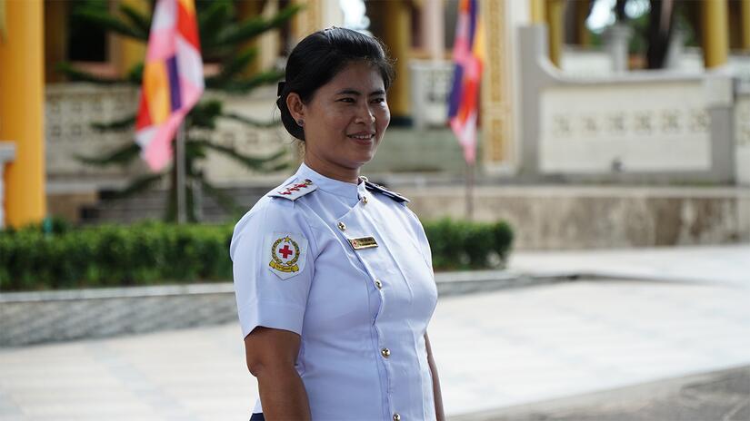 Myanmar Red Cross health worker, Thi Thi Mon, stands in her medical uniform ready to provide assistance to her community.