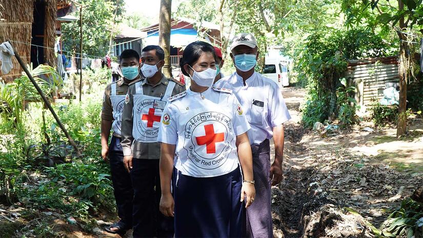 A team of Myanmar Red Cross Society health workers walk together through a rural community in Myanmar where they provide vital health services to the local population.