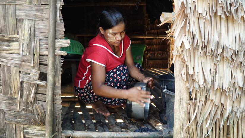 Mother Moe Thuzar crouches to wash her dishes in her home in Mon State, Myanmar.