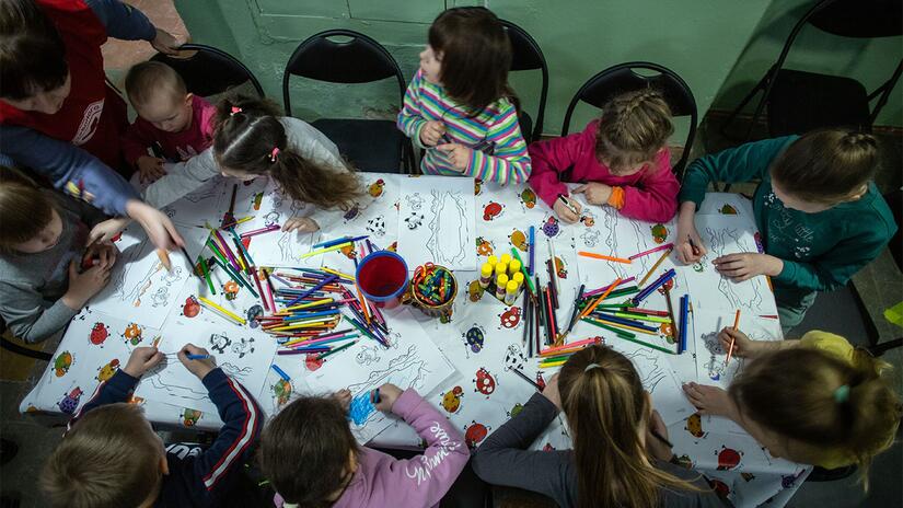 A group of children in Dnipro, Ukraine draw and play together as part of a psychosocial support session led by the Ukrainian Red Cross.