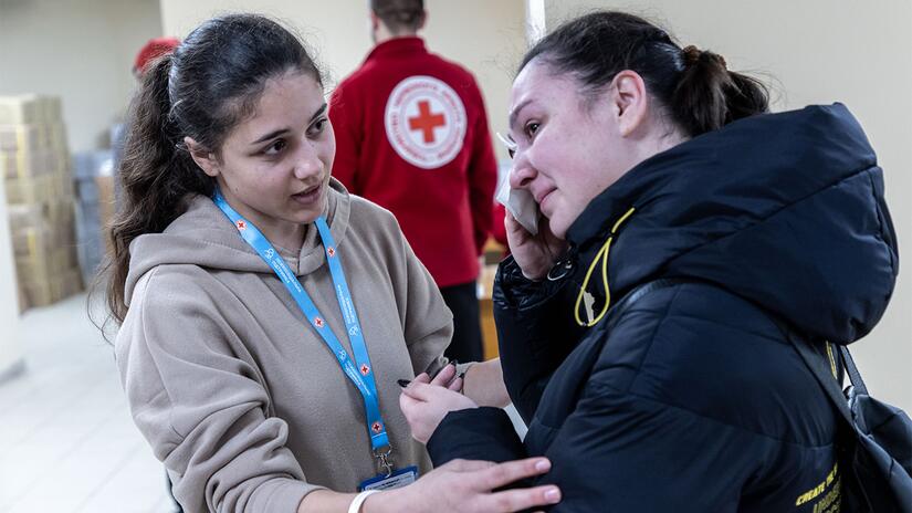 متطوعة في جمعية الصليب الأحمر الأوكراني تواسي امرأة من أوكرانيا متأثرة بالنزاع المسلح الدولي المستمر.  