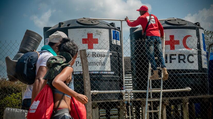 Un especialista en agua y saneamiento de la Cruz Roja Panameña inspecciona dos tanques de agua limpia que abastecen al centro de recepción de migrantes de San Vicente.