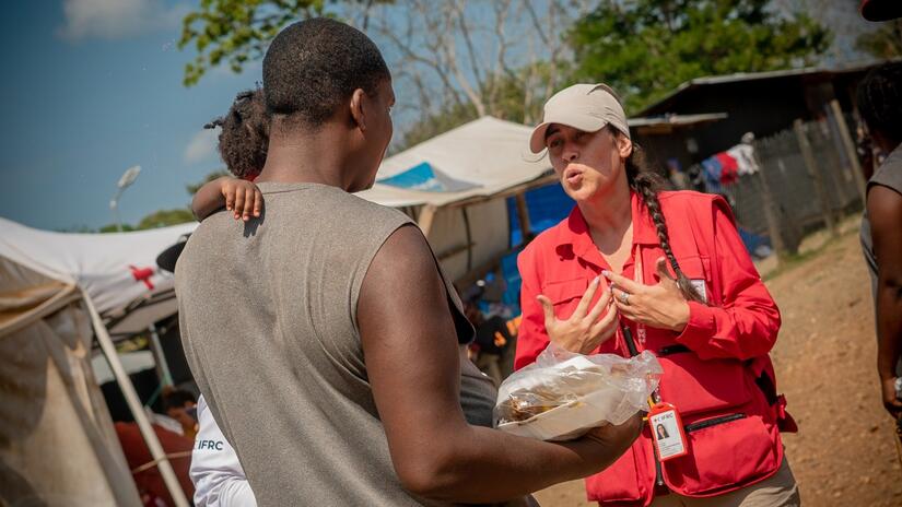 An IFRC worker speaks to a man and his child who have received support from the Red Cross in Panama in May 2023.