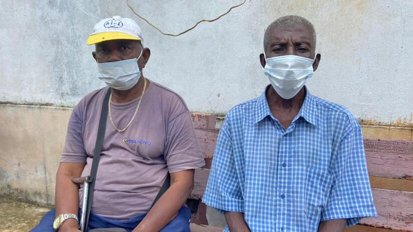 Manuel, left, sits with his friend in the welcome centre where he is a resident and receives daily support and care from the São Tomé and Príncipe Red Cross for his health, mental health and wellbeing.
