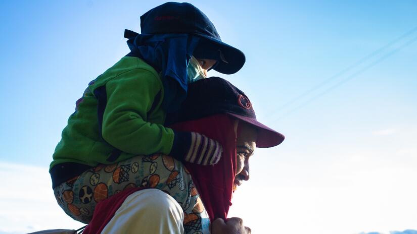Juan from Venezuela carries his young son, Santiago, on his shoulders as they make their way on foot to Bogota, Colombia in 2018 in search of a better life.