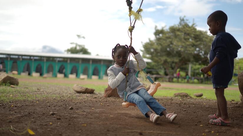 A young girl whose family are migrating through the Americas after having travelled from Africa plays on a swing in Costa Rica, her future uncertain.