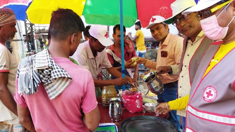 Indian Red Cross Society volunteers in Kandi, West Bengal offer cold water and shade to help people cope during a heat wave.