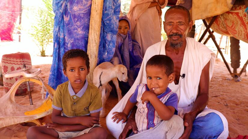 محمد، أب لسبعة أطفال، يجلس مع ثلاثة من أبنائه في منطقة المجرية، موريتانيا، حيث يكافح الكثير من الناس لإطعام أسرهم بسبب فيضانات عام 2022 التي قضت على محاصيل الناس.